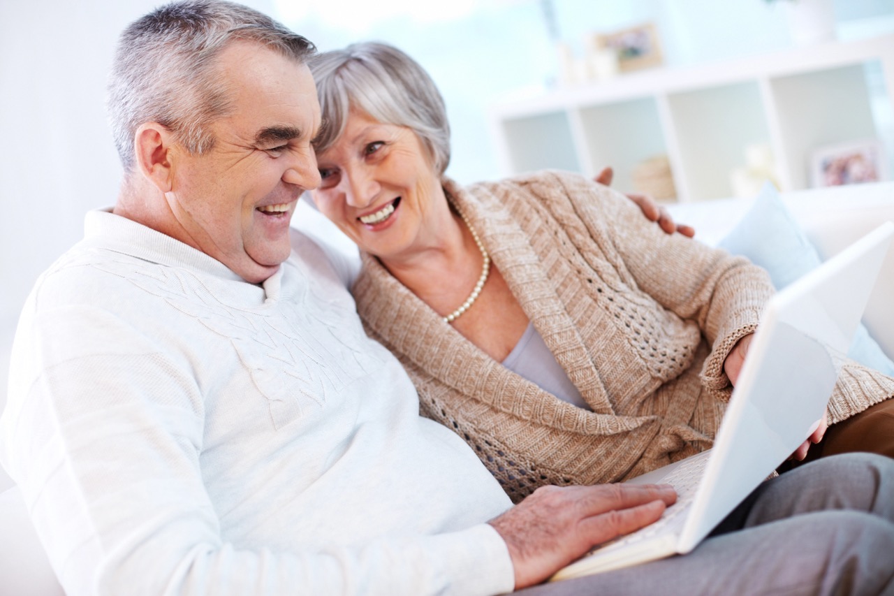 Portrait of mature man and his wife working with laptop at home