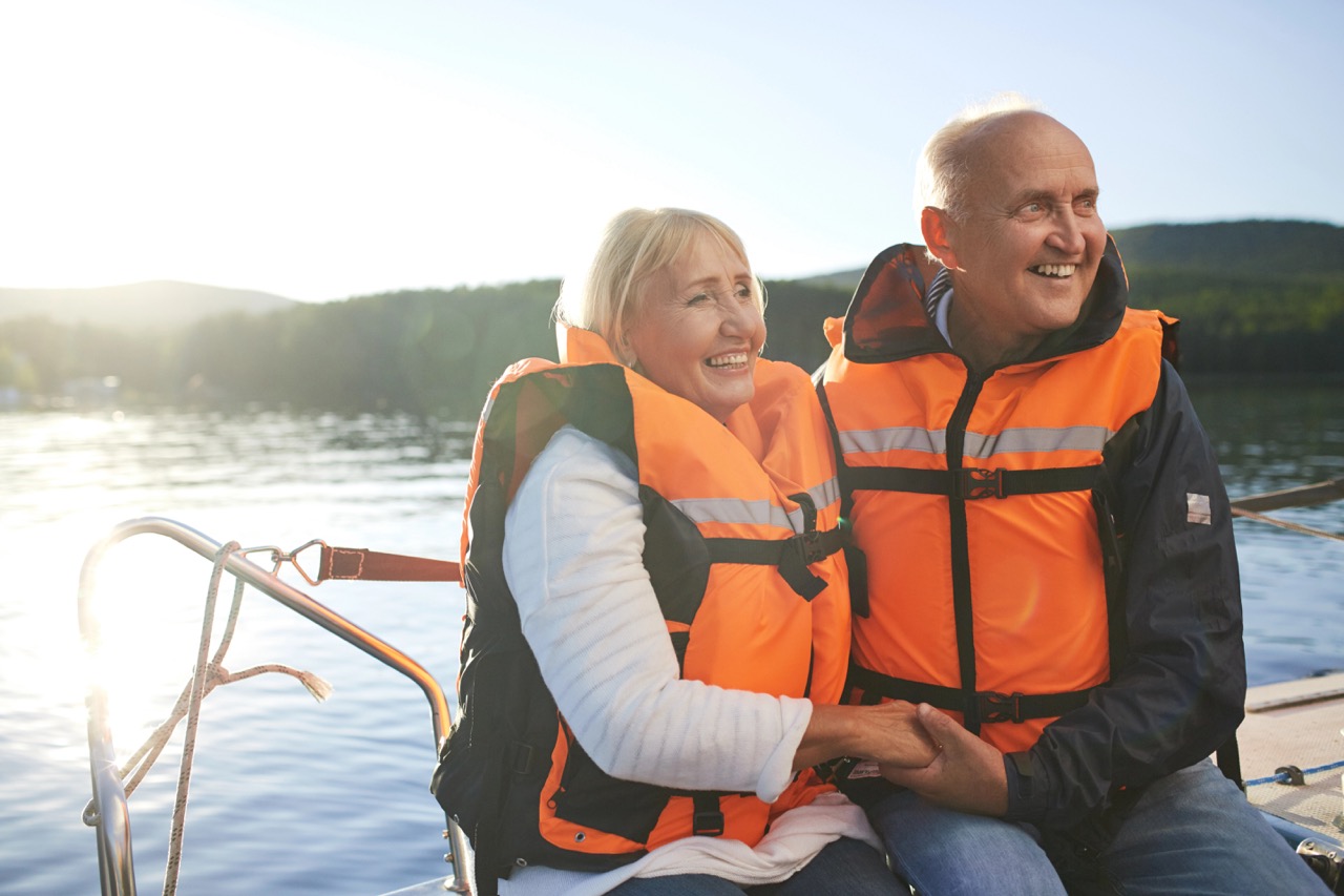 Active couple in life-vests sitting in yacht